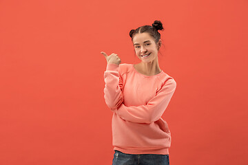 Image showing The happy woman standing and smiling against coral background.