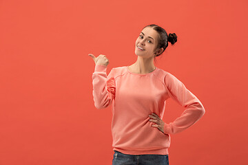 Image showing The happy woman standing and smiling against coral background.