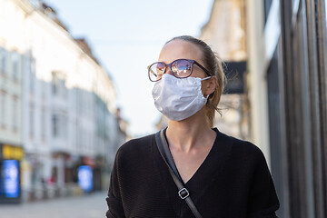 Image showing COVID-19 Pandemic Coronavirus. Young girl in city street wearing face mask protective for spreading of Coronavirus Disease 2019. Close up of young woman with medical mask on face against SARS-CoV-2.