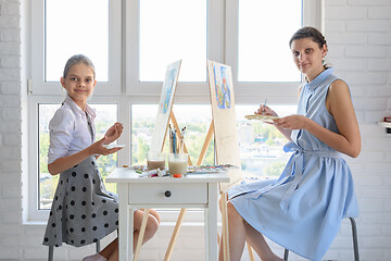 Image showing Girl and girl sit by the window and draw a picture, looked into the frame