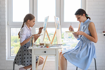 Image showing The girl learns to paint at the tutor, together they draw at the window