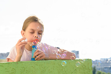 Image showing Girl blows bubbles on the balcony of a high-rise building