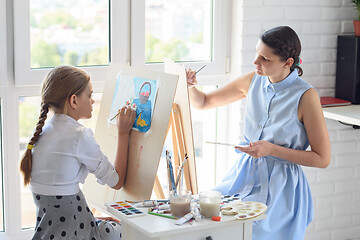 Image showing Mom and daughter draw on easels sitting at home by the window