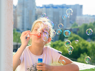 Image showing Girl blows a lot of soap bubbles from the balcony of the house