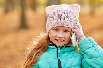 Image showing happy girl calling on smartphone at autumn park