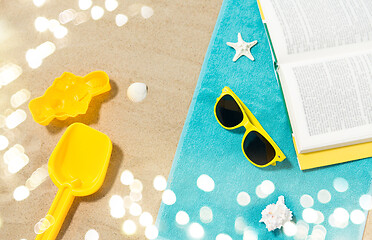 Image showing sunglasses, sand toys and book on beach towel