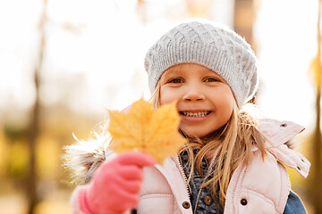 Image showing happy little girl with maple leaf at autumn park