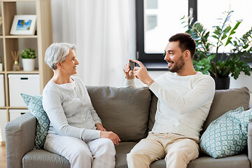 Image showing adult son photographing senior mother at home