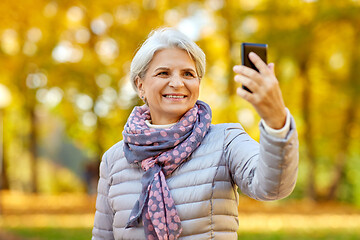 Image showing senior woman taking selfie at autumn park