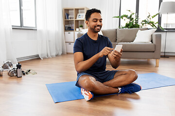 Image showing indian man with smartphone on exercise mat at home