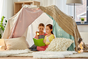 Image showing happy girls reading book in kids tent at home