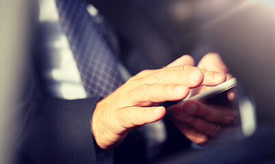 Image showing senior businessman texting on smartphone in car