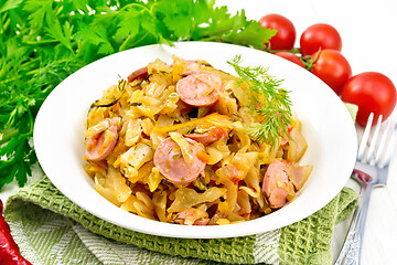 Image showing Cabbage stew with sausages in white plate on board