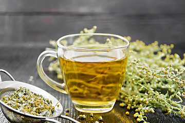 Image showing Tea of gray wormwood in glass cup with strainer on board