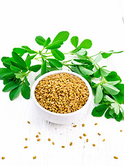 Image showing Fenugreek with green leaves in bowl on white wooden board