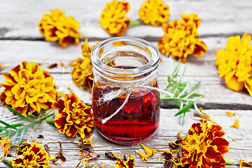 Image showing Alcohol tincture of marigolds in jar on wooden board