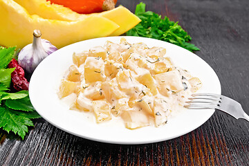 Image showing Pumpkin with sour cream sauce in plate on dark wooden board