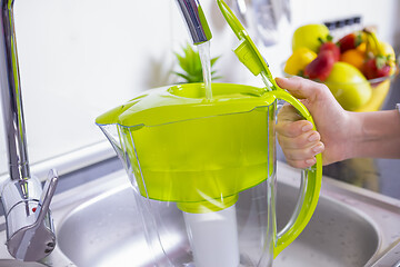 Image showing Woman filling water filter jug in the kitchen