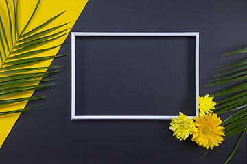 Image showing Frame of tropical palm leaves with flowers on black and yellow b