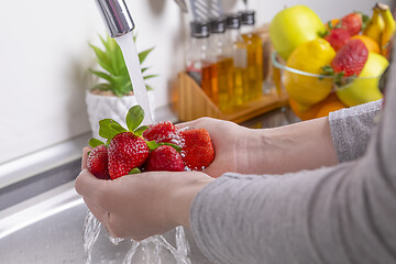 Image showing Woman washing strawberries in the kitchen