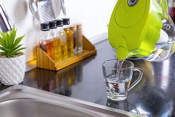 Image showing Pouring filtered water into glass from jug in the kitchen