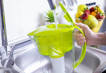 Image showing Woman filling water filter jug in the kitchen