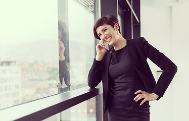 Image showing Elegant Woman Using Mobile Phone by window in office building