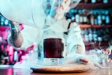 Image showing Expert barman is making cocktail at night club.