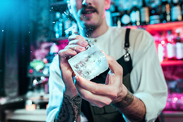 Image showing Expert barman is making cocktail at night club.