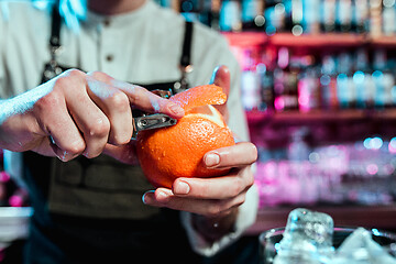 Image showing Expert barman is making cocktail at night club.