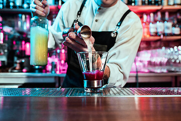 Image showing Expert barman is making cocktail at night club.