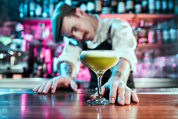 Image showing Expert barman is making cocktail at night club.