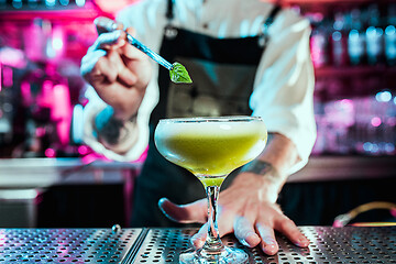 Image showing Expert barman is making cocktail at night club.