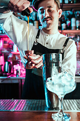 Image showing Expert barman is making cocktail at night club.