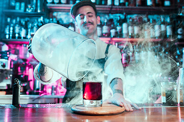 Image showing Expert barman is making cocktail at night club.