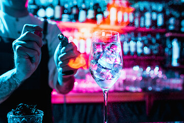 Image showing Expert barman is making cocktail at night club.