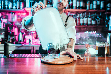 Image showing Expert barman is making cocktail at night club.