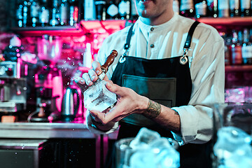 Image showing Expert barman is making cocktail at night club.