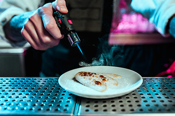 Image showing Expert barman is making cocktail at night club.