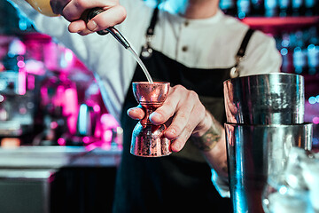 Image showing Expert barman is making cocktail at night club.