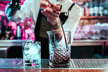 Image showing Expert barman is making cocktail at night club.