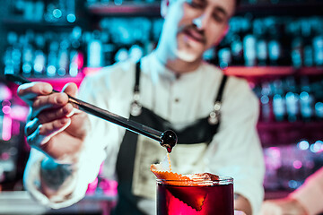 Image showing Expert barman is making cocktail at night club.