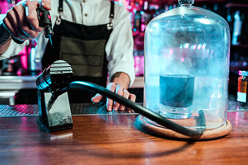 Image showing Expert barman is making cocktail at night club.