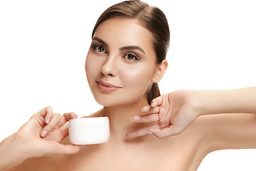 Image showing Cute girl preparing to start her day. She is applying moisturizer cream on face.