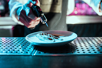 Image showing Expert barman is making cocktail at night club.