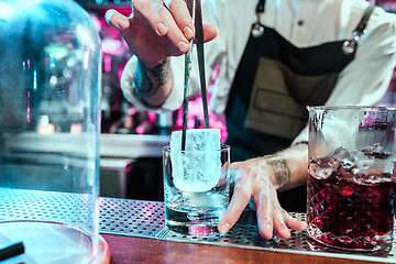 Image showing Expert barman is making cocktail at night club.