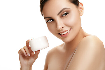 Image showing Cute girl preparing to start her day. She is applying moisturizer cream on face.