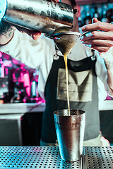 Image showing Expert barman is making cocktail at night club.