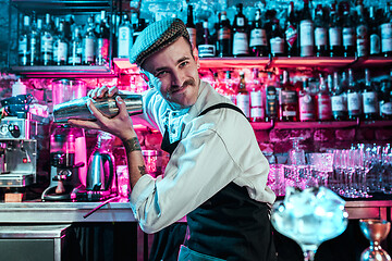 Image showing Expert barman is making cocktail at night club.