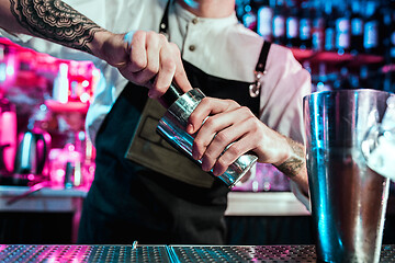 Image showing Expert barman is making cocktail at night club.